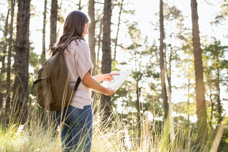 Brunette hiker reading map in the nature